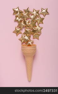 Ice cream sweet wafer cone with shiny golden stars on pink pastel background flatlay