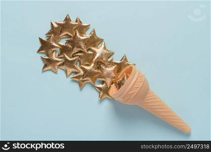 Ice cream wafer cone with golden stars on blue pastel background top view