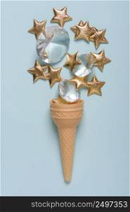 Ice cream wafer cone with shiny golden stars and gems on blue pastel background top view