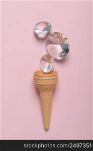 Ice cream waffle cone with shiny gems on pink pastel background flat lay