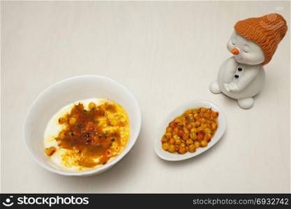 Ice cream with berries of sea-buckthorn and snowman figurine