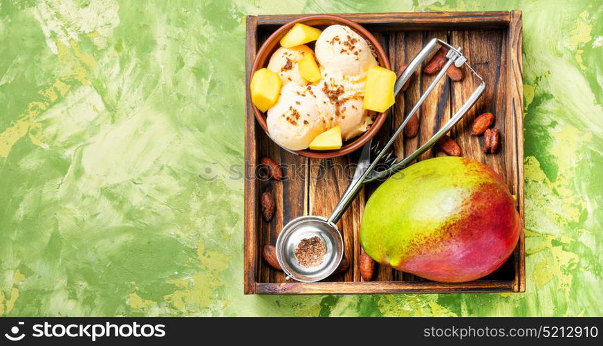 Ice cream with mango flavor. Ice cream, mango fruit and a spoon for ice cream in wooden tray