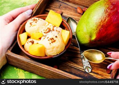 Ice cream with mango flavor. Ice cream, mango fruit and a spoon for ice cream in wooden tray