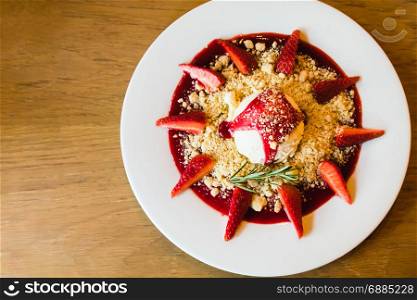 Ice cream with strawberry and cookie crumble on white dish