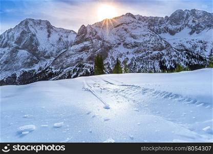 Ice crust over snowy mountains and pastures - Alpine scenery on a bright day of winter, with details over the crust of ice, that lies on the surface of the Austrian Alps pastures and is due to the warmth of the sun, that shines from behind the rocky peaks.
