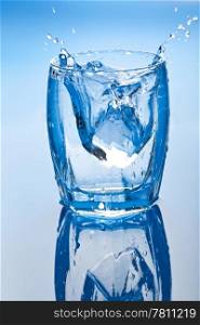 ice cube splashing into glass of water