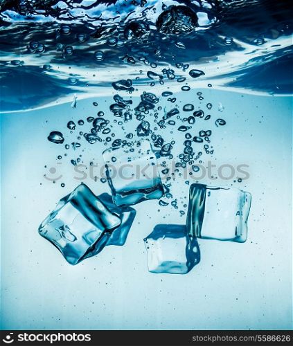 Ice cubes falling into the water sinking to the bottom. Abstract background.