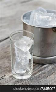 ice cubes. Glass with ice cubes and Ice bucket filled with ice cubes