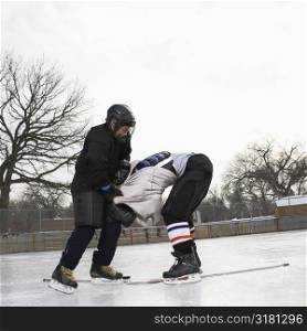 Ice hockey player boy roughing up another player on the ice rink.