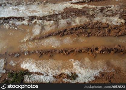 ice on mud red clay soil road with tyres lines