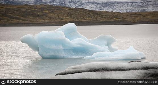 Iceberg melting in ocean water next to coastline