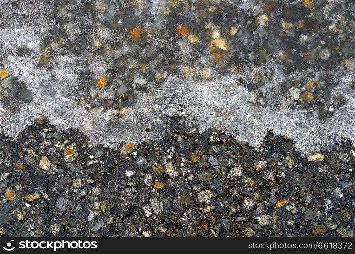 Iced asphalt road pavement detail in winter