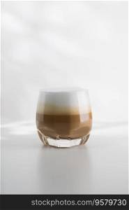 Iced cappuccino in a plastic glass on a white wooden table