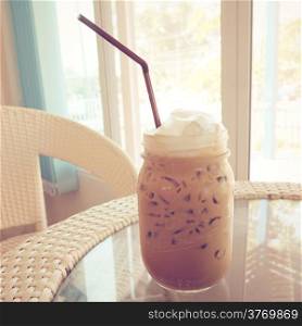 Iced coffee and straw on table with retro filter effect