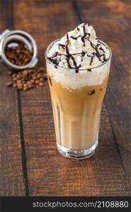 Iced coffee frappe with whipped cream in glass cup on wooden table
