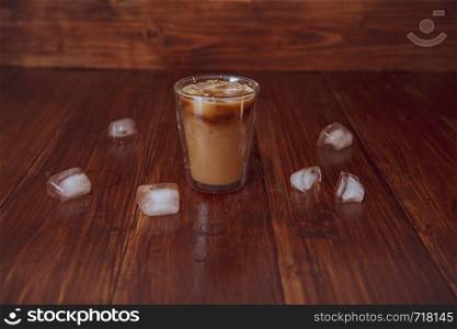 Iced coffee with ice cubes on table.. Iced coffee with ice on table