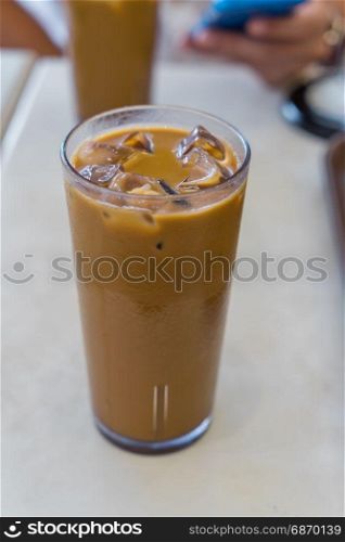 Iced coffee with milk in a tall glass on white table in Cafe shop