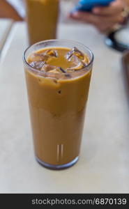 Iced coffee with milk in a tall glass on white table in Cafe shop