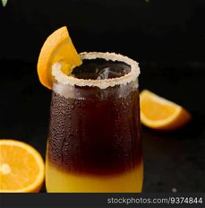 Iced coffee with orange juice in a transparent glass, refreshing bumble coffee on the table, black background