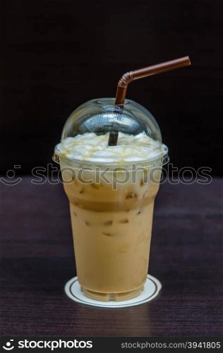 Iced coffee with straw in plastic cup. Cold coffee drink with ice on a table