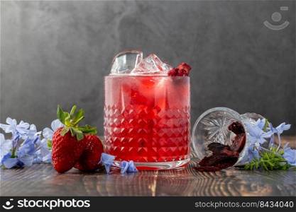Iced cold strawberry tea with slices of dried strawberries on wooden table