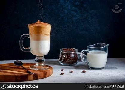 Iced Dalgona Coffee with Sifting Cocoa on Light Grey and Dark Background. Trendy Creamy Whipped Coffee. South Korean Cold Summer Drink.. Dalgona Coffee with Sifting Cocoa on Dark Background. Trendy Creamy Whipped Coffee. South Korean Cold Summer Drink