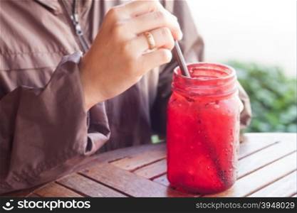 Iced drink in red glass on wooden table with vintage filter, stock photo