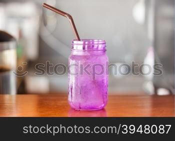 Iced drink in violet glass in coffee shop with vintage filter, stock photo