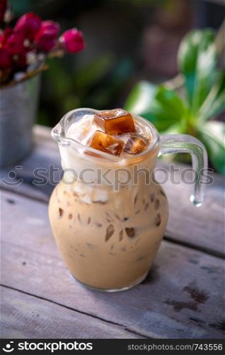 Iced latte in the glass on wooden table background.