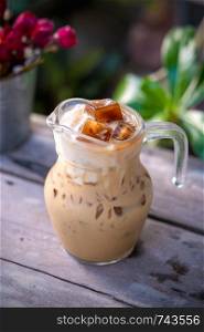 Iced latte in the glass on wooden table background.