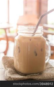 Iced milk coffee glass on wooden table with vintage filter effect, stock photo