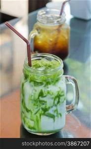 iced milk green tea. iced milk green tea with drinking straw on table