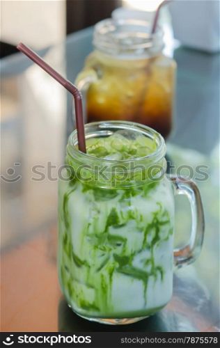 iced milk green tea. iced milk green tea with drinking straw on table