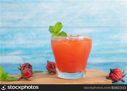 Iced roselle tea glass with fresh roselle fruit on wooden table for healthy herbal drink concept. herbal organic tea for good healthy.