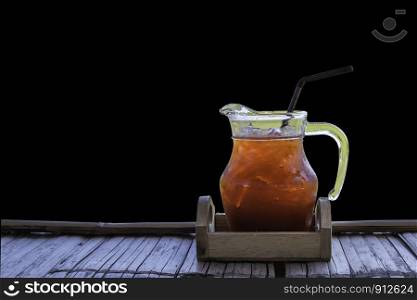 Iced tea in a glass jar on Bamboo flooringon a black background.