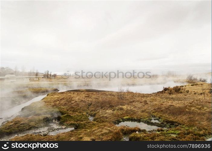 iceland hot springs with mist clouds and brown grass