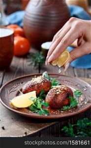 Ichli kyufte (Icli kufta) cutlets or meatballs covered with bulgur, sprinkled with walnuts, a hearty meat dish - the cuisine of the Middle East. Lemon juice drips onto the kyufta. Close-up
