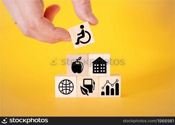 Icons for disabled people on wooden cubes, yellow background. The concept of assistance to the elderly and disabled.. Icons for disabled people on wooden cubes, yellow background.