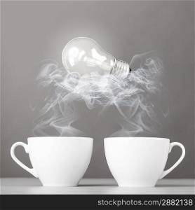 idea birth. bulb is lying on steaming hot coffee cups