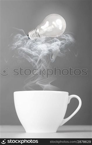 idea. bulb is lying on steaming hot coffee cup