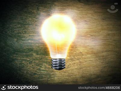 Idea concept. Background image with bright light bulb against cement wall