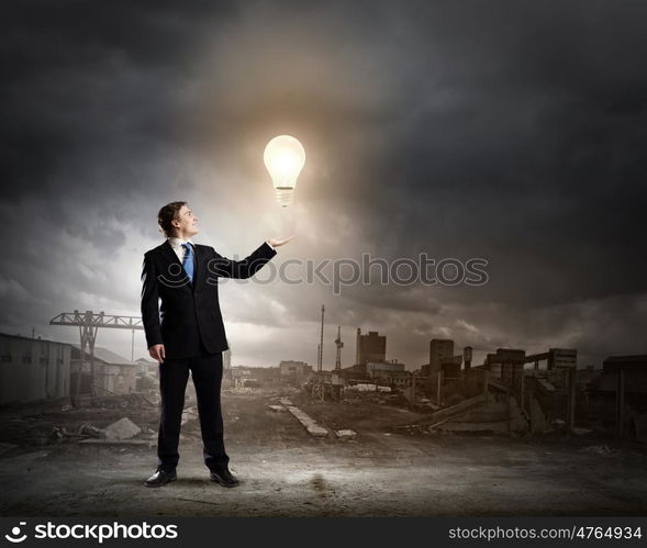 Idea concept. Businessman in suit holding light bulb in palm