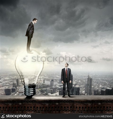 Idea concept. Businessman standing on top of light bulb and looking down