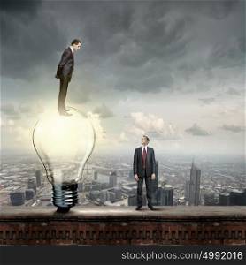 Idea concept. Businessman standing on top of light bulb and looking down