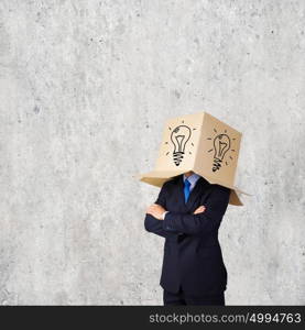Idea concept. Businessman wearing on head carton box with drawing of bulb