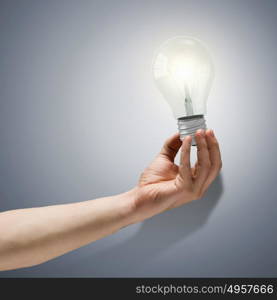 Idea concept. Close up image of human hand holding electrical bulb