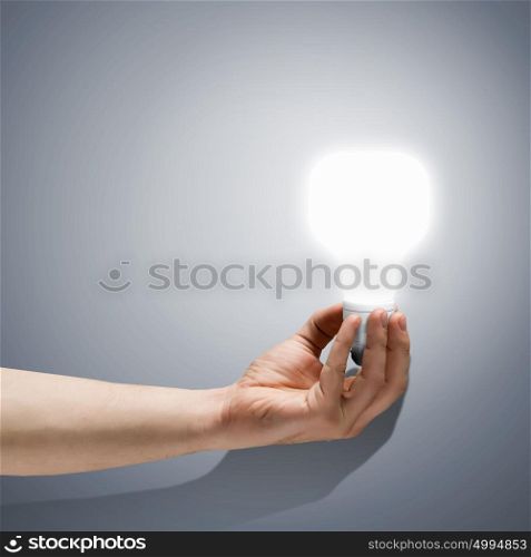 Idea concept. Close up image of human hand holding electrical bulb