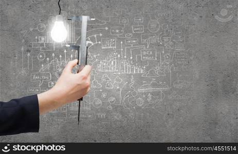 Idea concept. Close up of business person hand measuring bulb