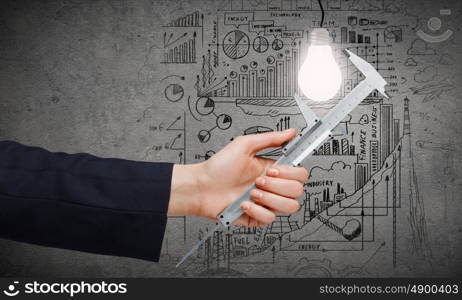 Idea concept. Close up of business person hand measuring bulb