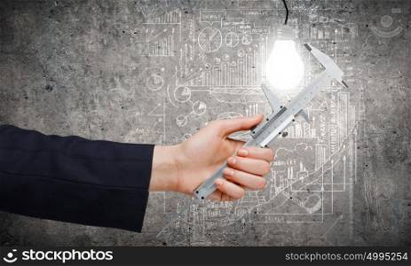 Idea concept. Close up of business person hand measuring bulb